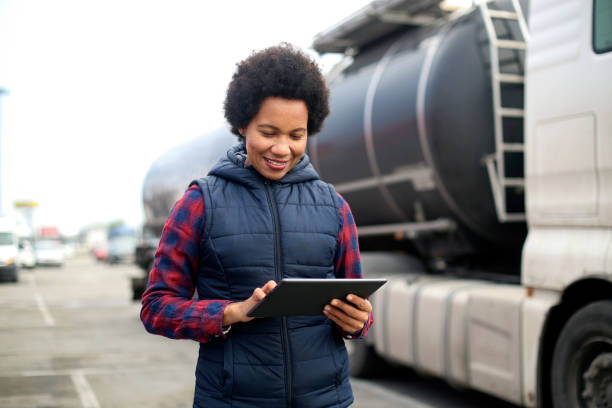 Mid adult female fuel truck driver using a tablet. About 40 years old, African woman.